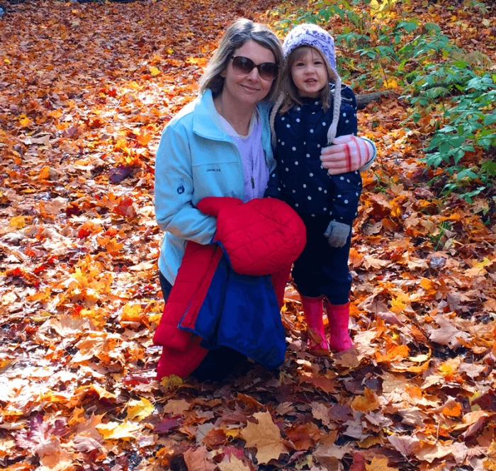 Melanie and daughter playing in the fall leaves